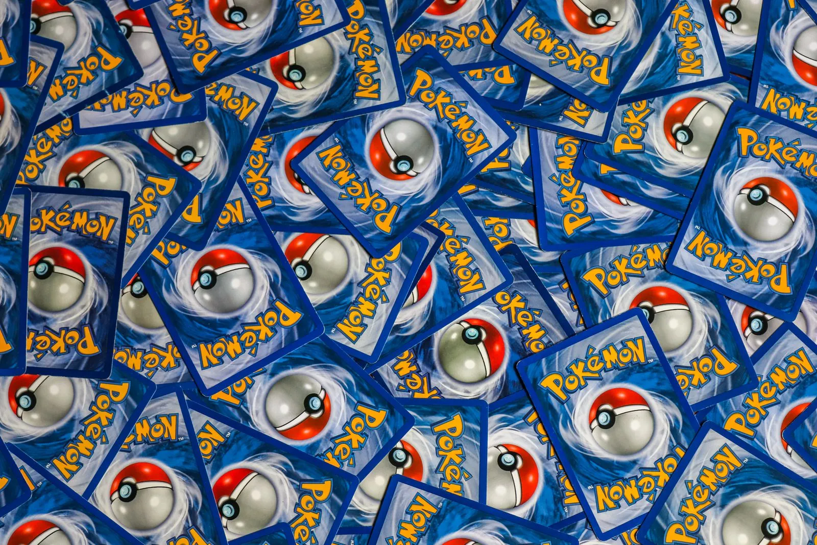 Dos de cartes Pokémon éparpillés, avec le logo Pokémon et la Poké Ball