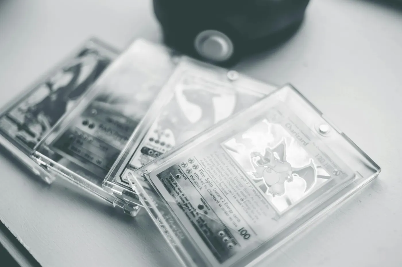 Cartes Pokémon vintage dans des boîtiers transparents photographiées en noir et blanc — l'authentification nécessite un examen méticuleux.